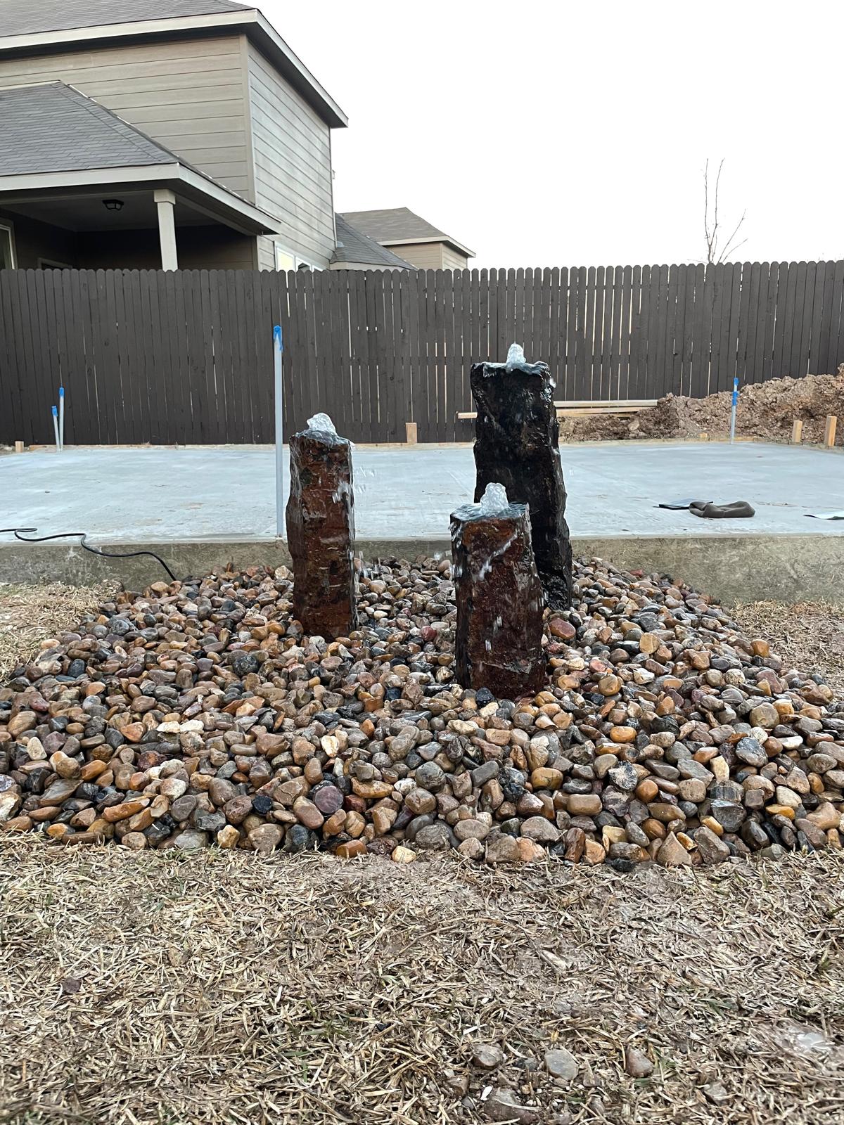 Rock water feature and decorative landscaping by Risen Remodeling